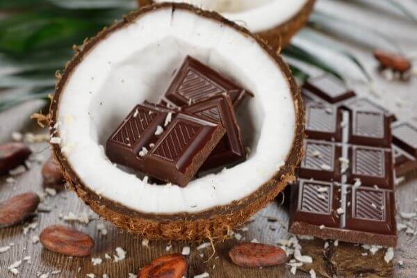 Crna čokolada u kokosovom orahu na stolu sa plodovima kakaovca